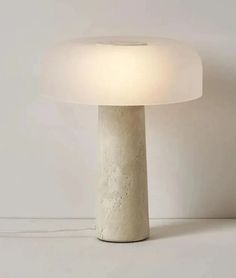 a white table lamp sitting on top of a floor next to a wall mounted light