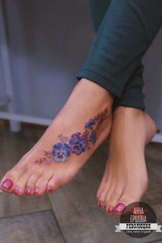 a woman's foot with purple flowers on it