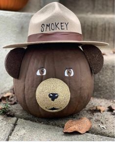 a pumpkin with a bear face painted on it's side and a hat that says smokey