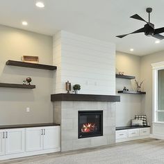 an empty living room with a fireplace and shelves