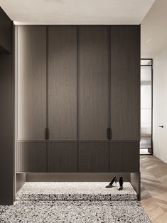 an empty room with wooden closets and black shoes on the floor in front of it