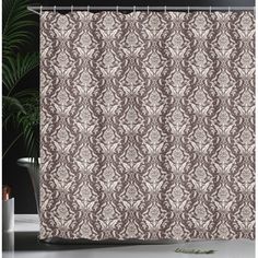 a shower curtain with a brown and white pattern on the outside, in front of a potted plant