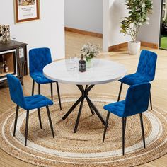 a white table with blue chairs and a rug on the floor in front of it