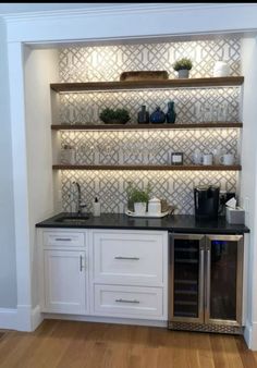 an empty kitchen with white cabinets and black counter tops, along with shelves that have plants on them