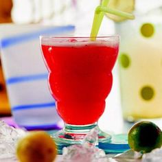 a red drink in a glass with a green straw sticking out of it's top