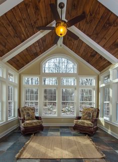 a living room with two chairs and a rug on the floor in front of windows