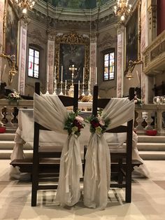 two chairs with sashes tied to them in front of a church alter decorated for a wedding