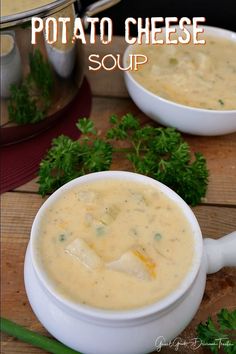 two bowls of potato cheese soup on a wooden table with parsley in the background