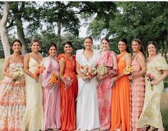 a group of women standing next to each other wearing dresses and holding bouquets in their hands