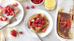 french toast with strawberries and orange juice on a white tablecloth next to plates