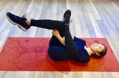 a woman laying on top of a red yoga mat