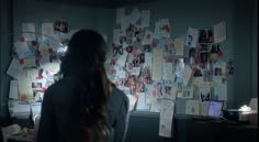 a woman standing in front of a wall covered with papers