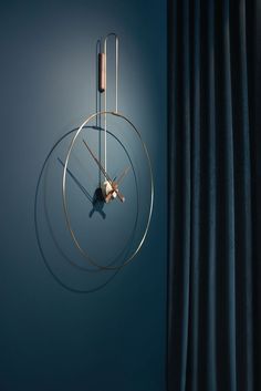 a clock that is hanging on the wall next to a blue curtain and drapes