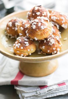 some sugar covered donuts in a bowl on top of a napkin and table cloth