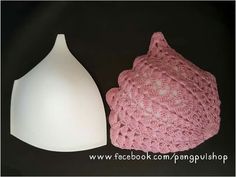 a pink crocheted hat next to a white plastic object on a black surface