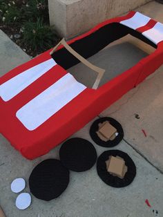 a cardboard boat sitting on top of a sidewalk next to some cut up pieces of paper