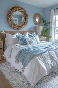 a bedroom with blue walls, white bedding and an oval mirror on the wall