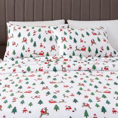 a bed with christmas themed sheets and pillows