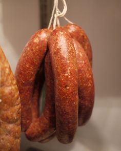 two sausages hanging from hooks on a wall