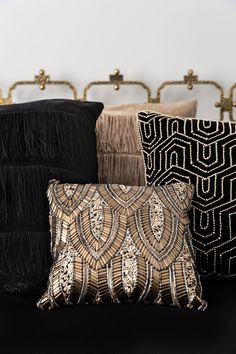 black and gold pillows are sitting on a couch with other decorative items in the background