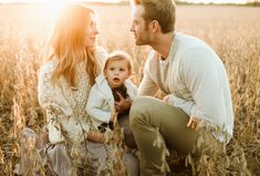 a man, woman and child are sitting in the middle of a field with tall grass