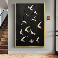 a black and white painting with birds flying in the air on a gray wall next to stairs