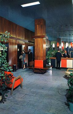 an office lobby filled with lots of plants and people standing in the doorway to it