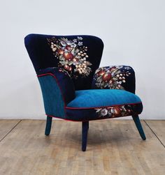 an upholstered blue chair with floral designs on the armrests and back