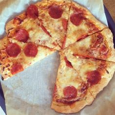 the pizza is cut into four slices and sits on wax paper in front of it