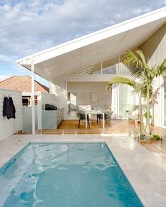 an empty swimming pool in the middle of a house with a covered patio and dining area