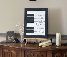 a piano sign sitting on top of a wooden table next to a vase filled with baby's breath