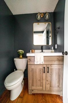 a white toilet sitting next to a wooden cabinet in a bathroom under a large mirror