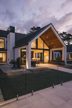 a modern house is lit up at night in the evening with large windows and an open floor plan