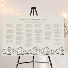 a wedding seating chart on a easel in front of a string of christmas lights