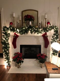 a fireplace decorated for christmas with stockings and poinsettis