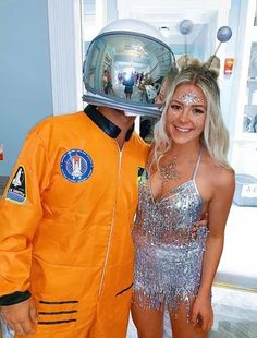 a man in an orange astronaut suit and woman in silver dress posing for the camera