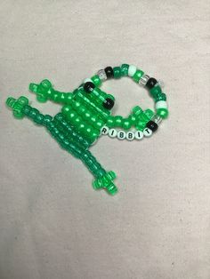 a green and white beaded bracelet with an alligator on it