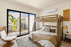 a bed room with a neatly made bed next to a sliding glass door and a chair