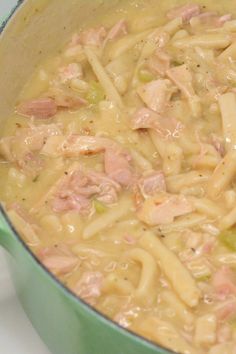 a green pot filled with pasta and meat