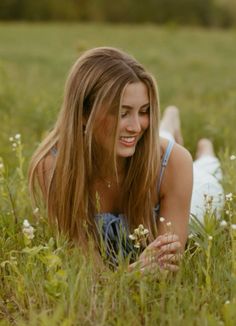 a young woman laying in the grass with her eyes closed and looking up at something