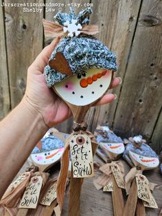 a hand holding a small snowman ornament on top of a wooden pole