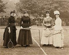 three women standing on a tennis court holding racquets and posing for the camera