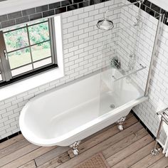 a white bath tub sitting on top of a wooden floor next to a radiator