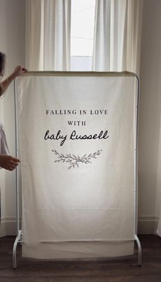 a woman standing in front of a white banner that says falling in love with baby russell