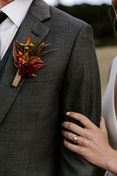 a close up of a person wearing a suit and tie with a boutonniere