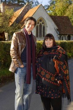 a man standing next to a woman in front of a church wearing a shawl