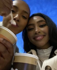 two people are posing for a photo with coffee cups in their hands and one person is holding a cup