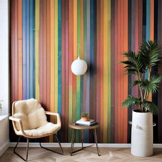 a chair and table in front of a wall with colorful stripes painted on it's walls