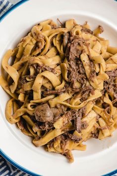 a white plate topped with pasta and beef