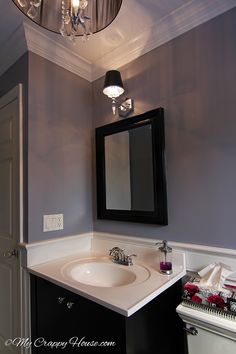 a white sink sitting under a mirror in a bathroom next to a light above it